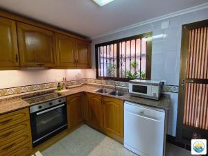 a kitchen with wooden cabinets and a sink and a microwave at Adosado Primera línea de mar Playa de Puzol con Piscina y terrazas in Playa de Mar