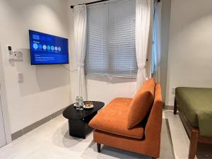 a living room with a chair and a flat screen tv at Cỏ Lá Homestay in Danang