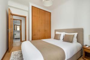 a bedroom with a large bed with a wooden door at Cinfães Centro Stay in Cinfães