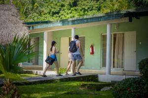 two women walking outside of a green house at Hotel Playa Azul in Catemaco
