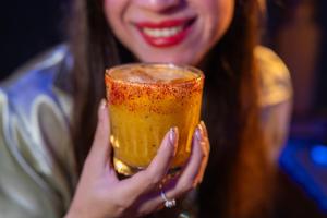 a woman holding up a glass of orange liquid at Hotel Playa Azul in Catemaco