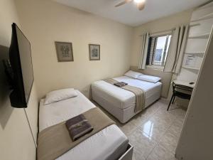 two beds in a room with a television and a desk at Casa do Loro Hospedagem in Curitiba