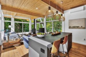 a kitchen with a large island in a room with windows at La Trêve Mont Tremblant in La Conception