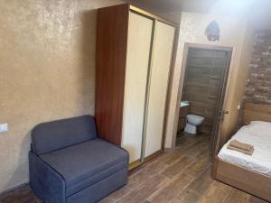 a bedroom with a blue chair and a bed at Тихий дворик in Odesa