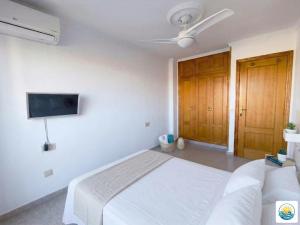 a white bedroom with a bed and a flat screen tv at Adosado Primera línea de mar Playa de Puzol con Piscina y terrazas in Playa de Mar +13 photos