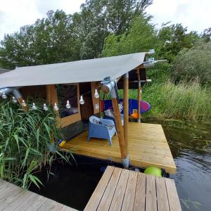 a small boat with a white canopy on the water at Safaritent 4 in Biddinghuizen