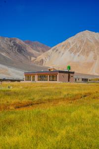 a building in a field with a mountain in the background at Eco Residence Pangong in Lukung