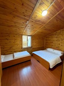 two beds in a room with wooden walls at Rif Burabay in Borovoye