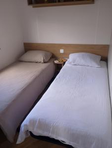 two beds sitting next to each other in a bedroom at Location mobil home in Litteau