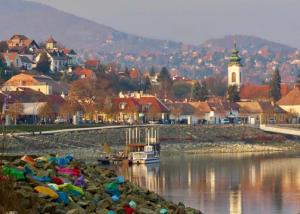 a river with a town and a boat in the water at 7Csakra Vendeghaz in Szentendre