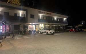 a white car parked in a parking lot in front of a building at HOTEL Monte Cimone in Caldonazzo