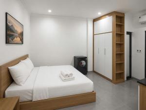 a bedroom with a white bed and a wooden cabinet at Dreamora Serenity Hotel & Residence in Hanoi