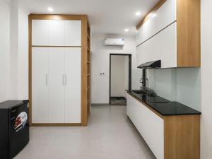 a kitchen with white cabinets and a black counter top at Dreamora Serenity Hotel & Residence in Hanoi