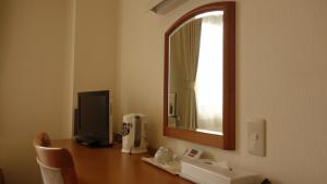 Habitación con escritorio, TV y espejo. en Hotel Green Selec, en Sendai