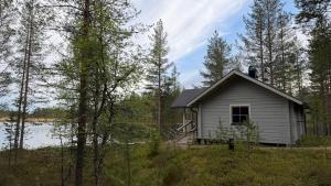 a small house in the woods next to a lake at Pitkälampi Private Lake Lodge in Jokikylä