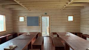 a large room with wooden tables and a tv at Pitkälampi Private Lake Lodge in Jokikylä
