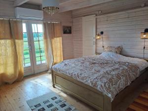 a bedroom with a large bed in a room with windows at Zeltarasa in Avotkalni
