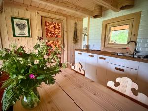 a kitchen with a vase of flowers on a wooden floor at Górska Osada Berdo in Chmiel +108 photos