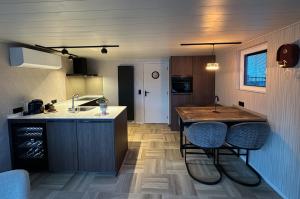 a kitchen with a sink and a counter with stools at De Waterlodge - Uniek verblijf aan het water in Franeker
