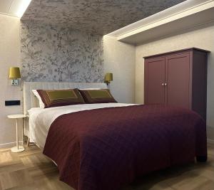a bedroom with a large bed with a purple blanket at De Waterlodge - Uniek verblijf aan het water in Franeker