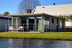 a house with glass doors on the side of the water at De Waterlodge - Uniek verblijf aan het water in Franeker
