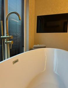 a bath tub in a bathroom with a tv at De Waterlodge - Uniek verblijf aan het water in Franeker +13 photos