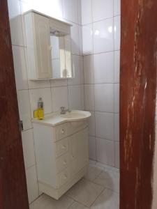 a white bathroom with a sink and a mirror at Suíte Gigá 1 in Brotas
