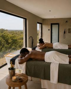 two men laying on beds in a room with a window at Sanyati Villa in Mmukubyane
