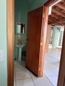 a bathroom with a door leading to a sink at Suíte GiGá 2 in Brotas +6 photos