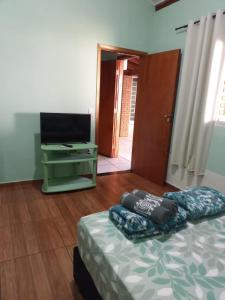 a living room with a bed and a television at Suíte GiGá 2 in Brotas