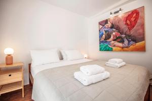 a white bedroom with a large painting on the wall at Central Art House Hvar in Hvar