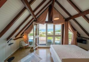 a bedroom with a bed and a large window at La Suite Villa in Les Trois-Îlets