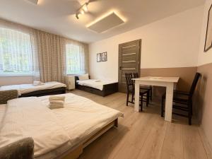 a room with two beds and a table and a desk at Park Leśnicki Homely Studios by BookingHost in Wrocław