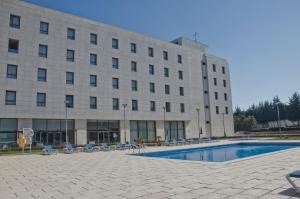 un bâtiment avec une piscine en face d'un bâtiment dans l'établissement VIP Executive Santa Iria Hotel, à Santa Iria da Azóia