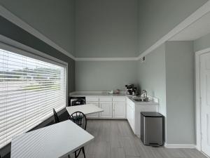 a kitchen with white cabinets and tables and a window at Travel Inn Buford near Mall of Georgia in Buford