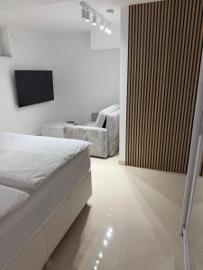 a white bedroom with a bed and a television at Ana Deluxe Apartment in Radovljica