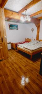 a bedroom with a bed and a wooden floor at Letni Domek , Ogrzewany, z bilardem in Ruciane-Nida