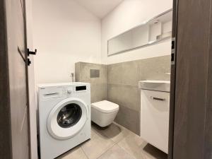 a bathroom with a washing machine and a toilet at Park Leśnicki Homely Studios by BookingHost in Wrocław