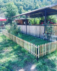 a fence in front of a house with a garden at Aygut Garden in Aygut +3 photos