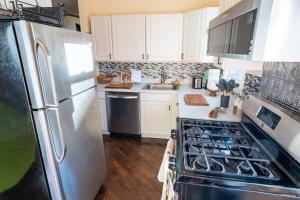 a kitchen with white cabinets and a stainless steel refrigerator at Bucktown Private Condo in Chicago +15 photos