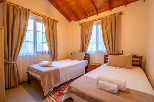 a bedroom with two beds and two windows at Villa Masal in Kayakoy +17 photos