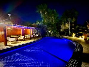 a blue swimming pool in front of a house at night at Villas do Pratagy VIP in Maceió