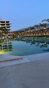 a large pool of water with tables and chairs at Lunea Apartment Palm Residence in Vlorë