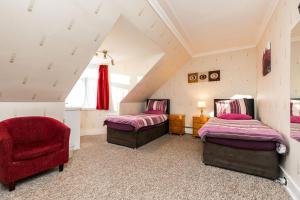 a attic bedroom with two beds and a red chair at Station View Guest House in Dyce