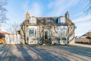 an old stone house with windows on a street at Station View Guest House in Dyce