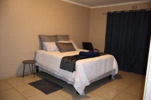 a bedroom with a bed with white sheets and pillows at MERK Guest House in Piet Retief