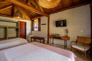 a bedroom with two beds and a tv on the wall at Casa Caroá - Chalé 1 in Japaratinga
