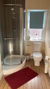 a bathroom with a shower and a toilet and a red rug at Lake District Gate in Lancaster +24 photos