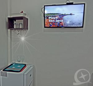 a flat screen tv hanging on a wall next to a refrigerator at Hotel Travel Encarnación in Encarnación