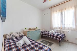 a bedroom with two beds and a dresser and a window at La Guzzetta Stintinese - Happy Rentals in Stintino